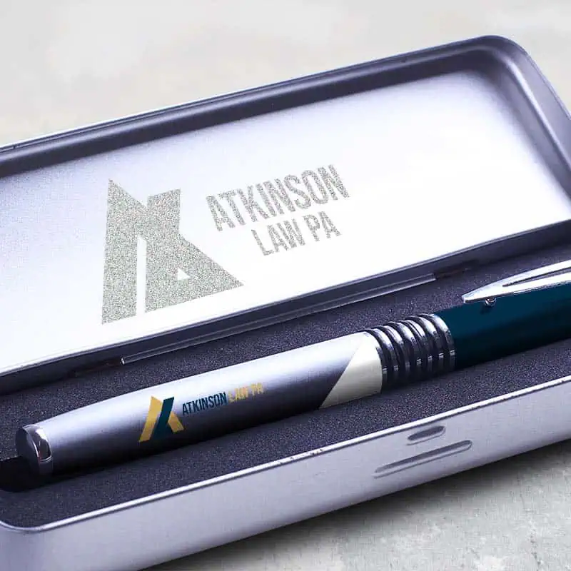 Executive pen with Atkinson Law logo resting in an engraved silver metal case