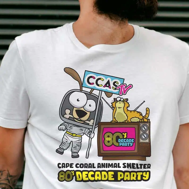 Young man with beard and tattooed arm wearing a white Cape Coral Animal Shelter 80s Decade Party t-shirt